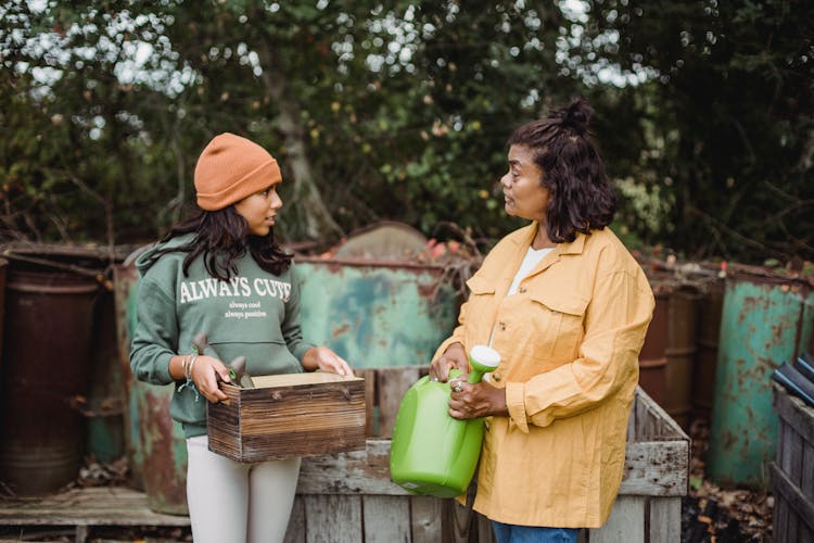 Ethnic Mother Talking To Daughter With Gardening Tools 