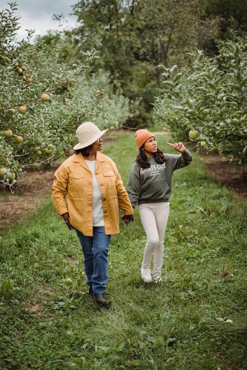 Unrecognizable ethnic mother with girl interacting while walking on farmland