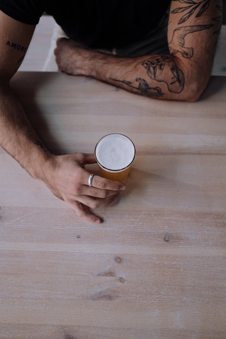 Overhead Shot Of A Person's Hand Holding A Glass Of Beer