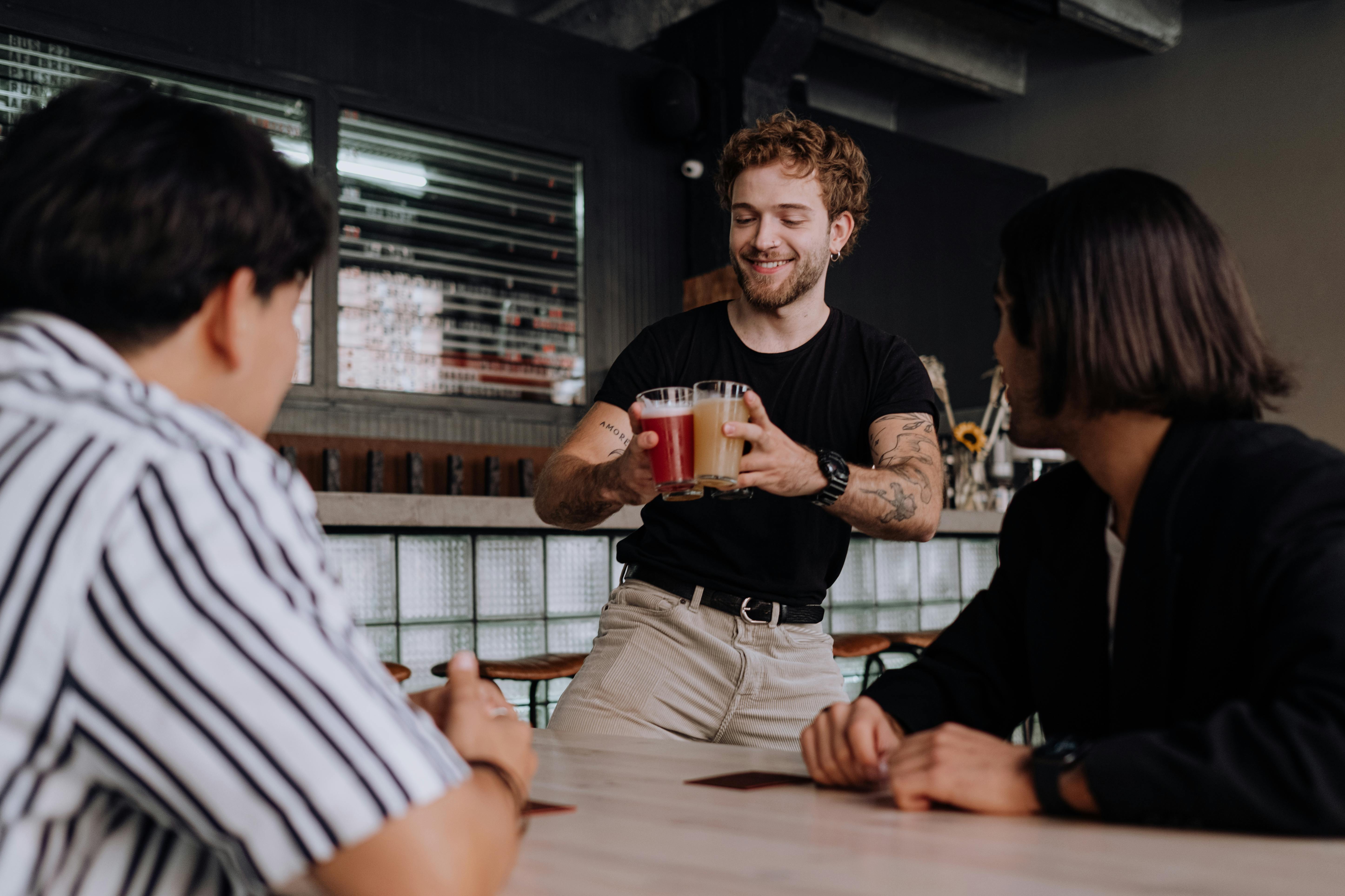 Three male friends enjoying drink at a bar. | Photo: Pexels