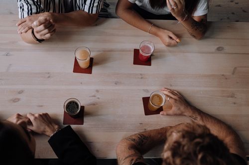 Free Aerial view of friends enjoying drinks at a cozy wooden table. Stock Photo