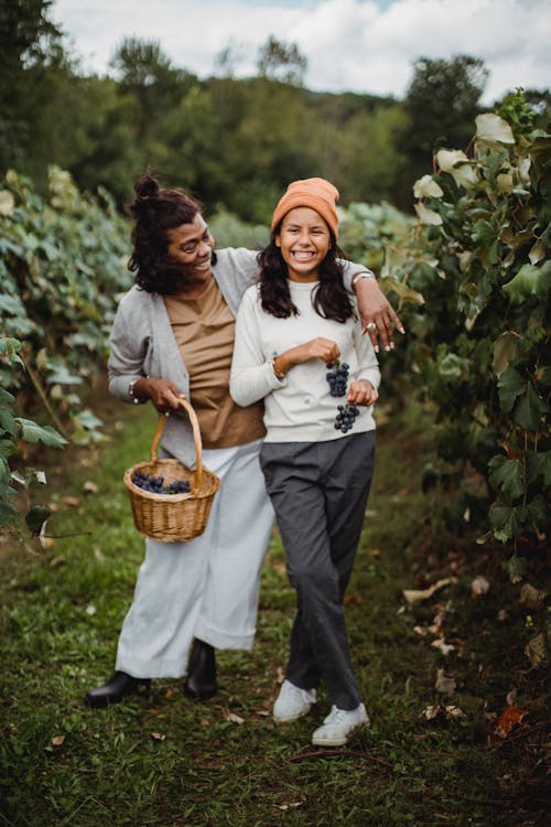 Cheerful ethnic gardener with daughter on path in vineyard
