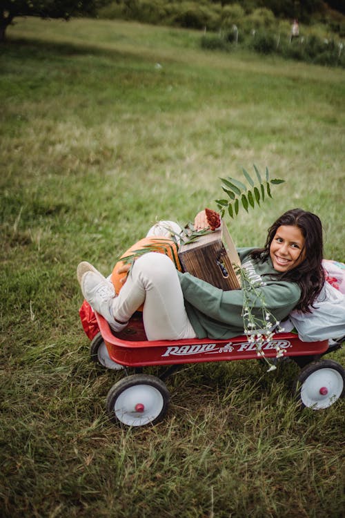 Ethnic girl with box and pumpkin in garden cart