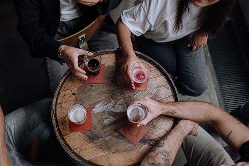 Free Overhead shot of friends enjoying drinks together at a round wooden table. Stock Photo