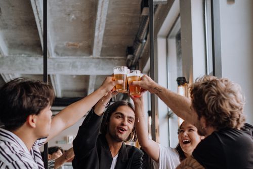 Free A group of young adults enjoying drinks and celebrating together in a trendy indoor bar. Stock Photo