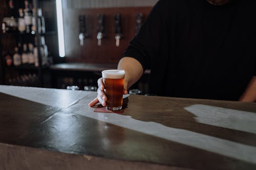 Photo of a Person's Hand Holding a Glass of Beer