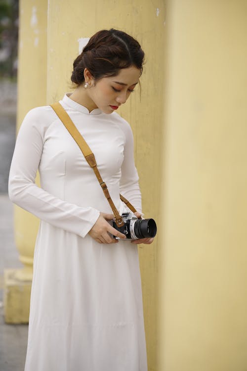 Stylish Asian woman taking photo near column