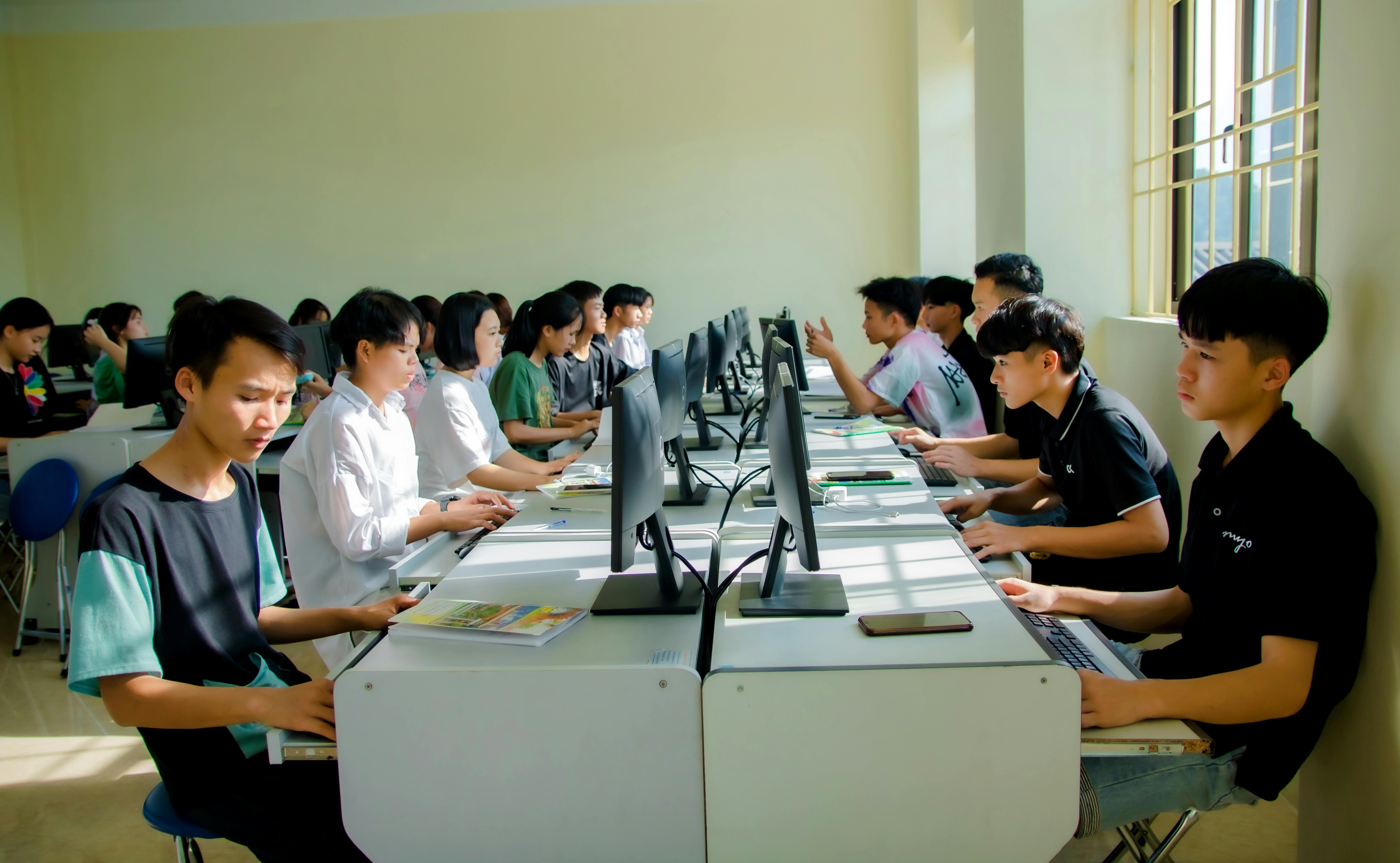 A group of students focused on computer tasks in a classroom setting, fostering teamwork.