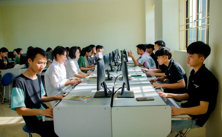 Group Of People Sitting On Chair In Front Of Computers In The Class