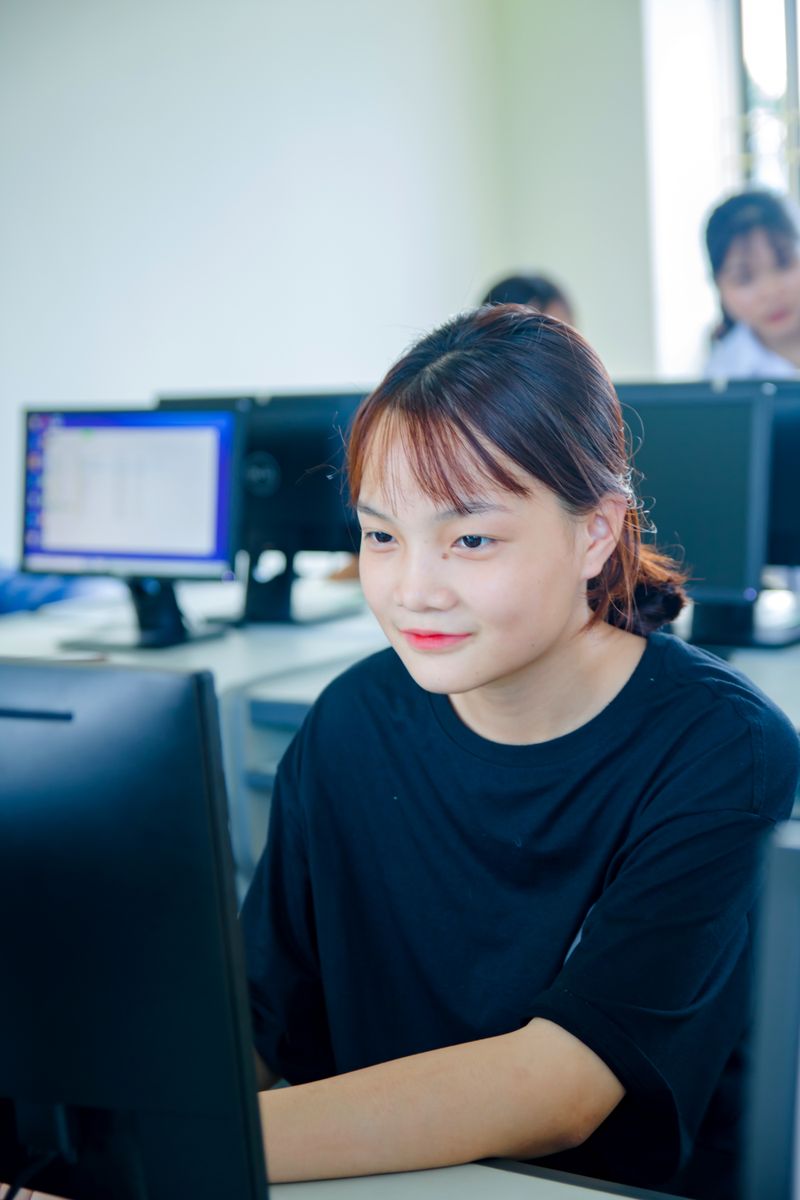 Asian student in a classroom engaging with computer for her studies, focused on learning.