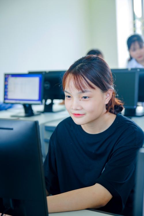 Woman in Black T-Shirt Using Computer and Smiling ยท Free Stock Photo