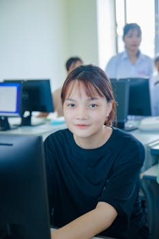 Asian girl studying in a university computer lab, focused on education and teamwork.