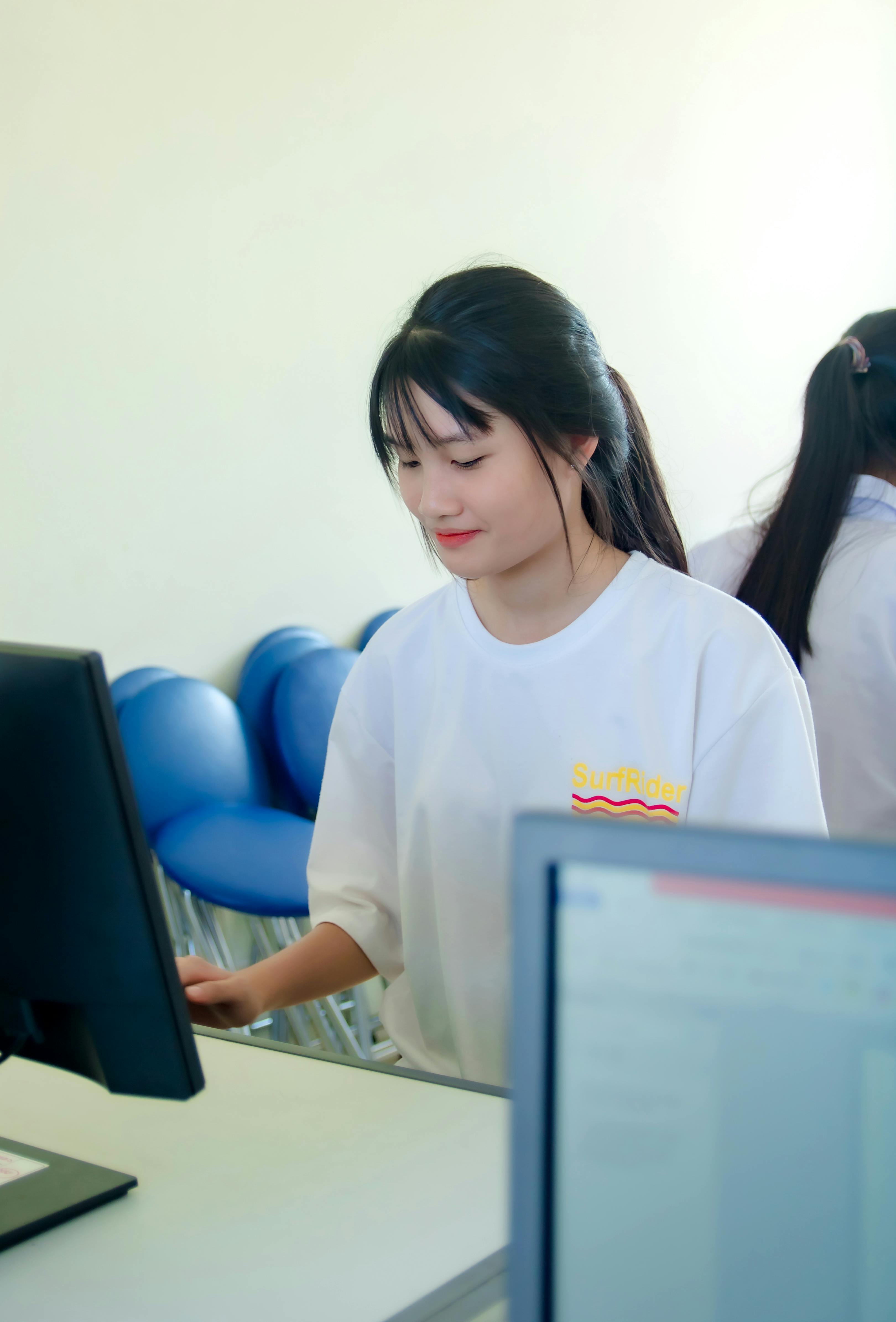 在明亮的办公环境中，亚洲女性正专注于计算机工作