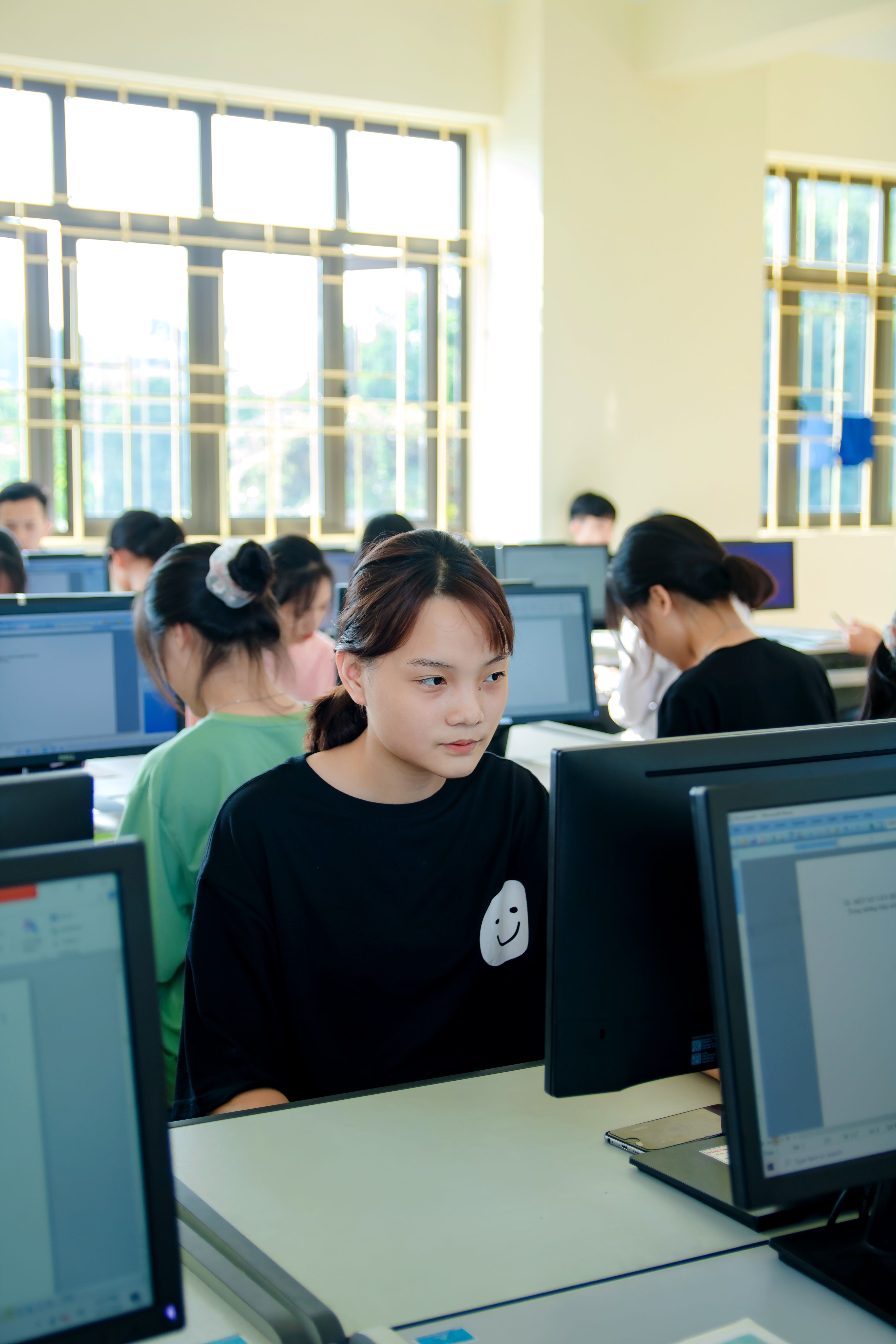 学生们在明亮的教室里专注地使用电脑