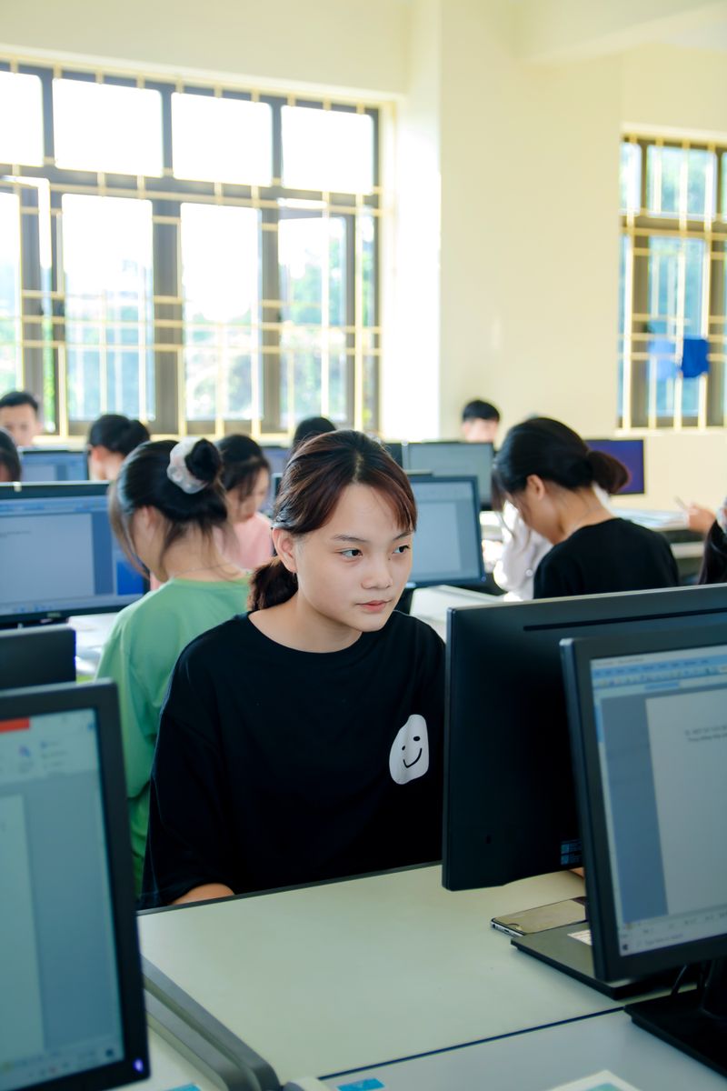 Students focused on computers in a bright classroom setting.