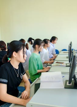 Students working at computers in a university classroom, focusing on assignments.