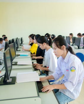Students focus on computer tasks in a classroom setting, emphasizing education and technology skills.