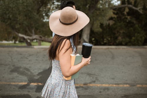 Faceless stylish woman with book walking on street