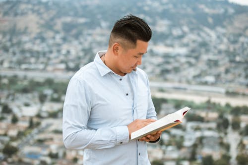 Man Wearing Long Sleeve Shirt Holding a Book