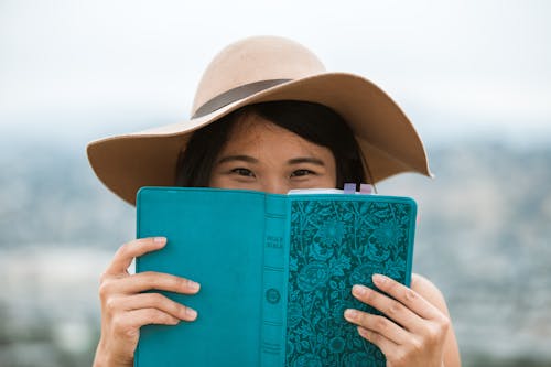 Woman in Brown Sun Hat Holding Blue Book