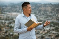 A Man in a Blue Long Sleeved Shirt Holding a Book of Harry Potter