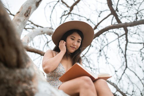 A Woman in a Hat Reading a Book