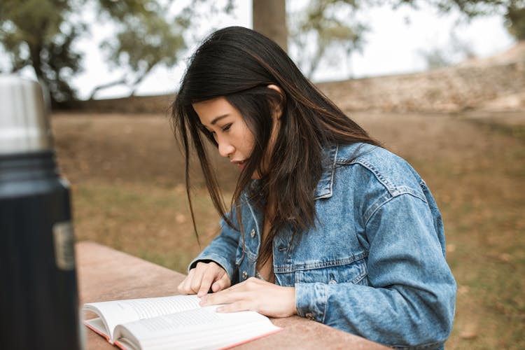 Woman In Denim Jacket Reading A Book