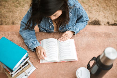 Free A Woman in Blue Denim Jacket Reading a Book Stock Photo