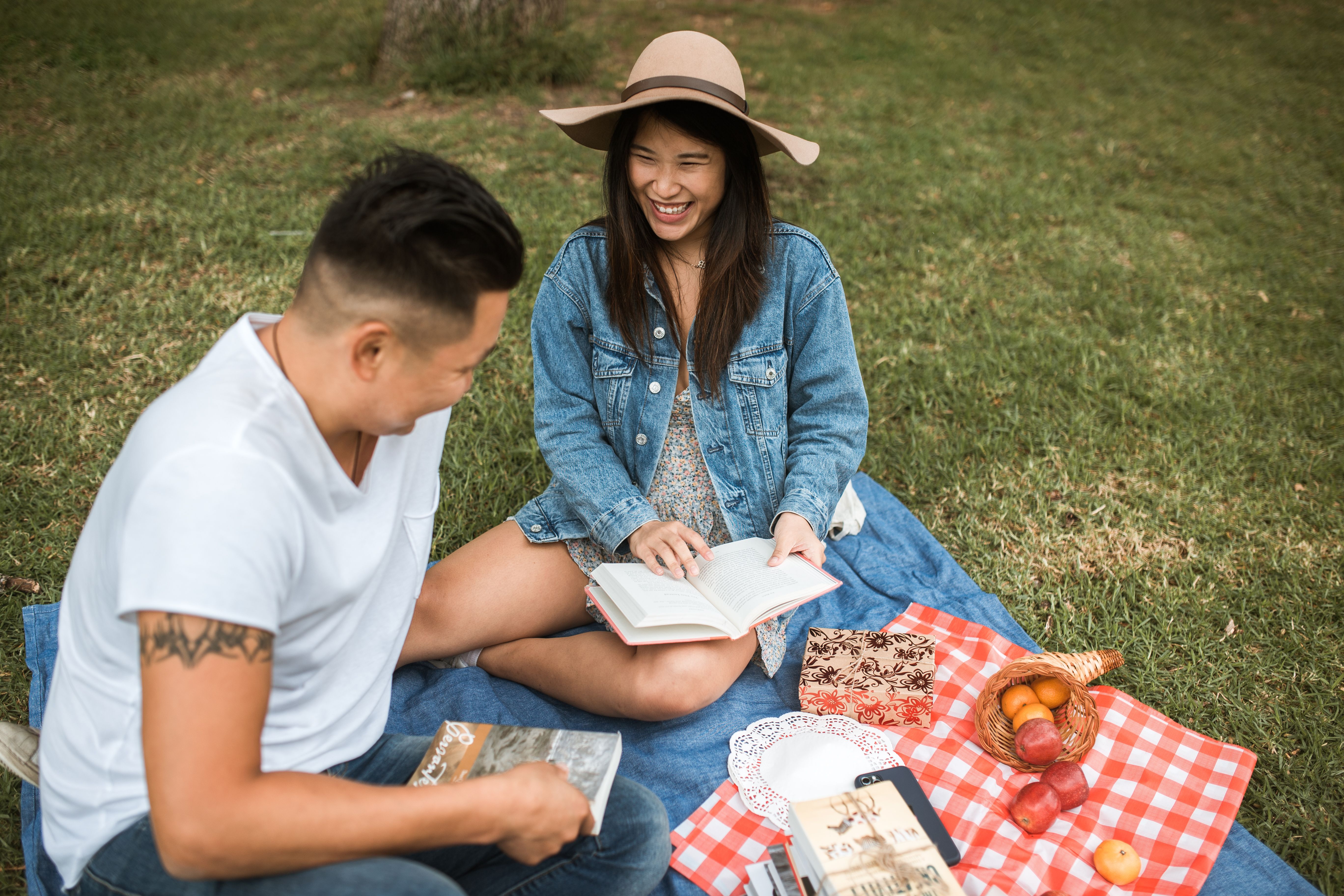 Happy couple reading books and enjoying a sunny day picnic outdoors.
