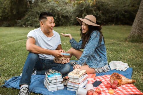 Free Couple Sitting on Picnic Blanket in the Park and Smiling Stock Photo