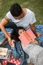一对夫妇在阳光明媚的公园里读书，享受轻松惬意的午后野餐