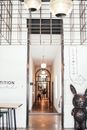 Distant people standing in narrow long light hallway of contemporary hotel with white walls metal decorations and hanging glowing lamps