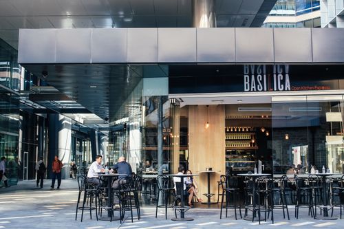 Free Outdoor cafe scene with seated patrons and modern urban architecture. Stock Photo