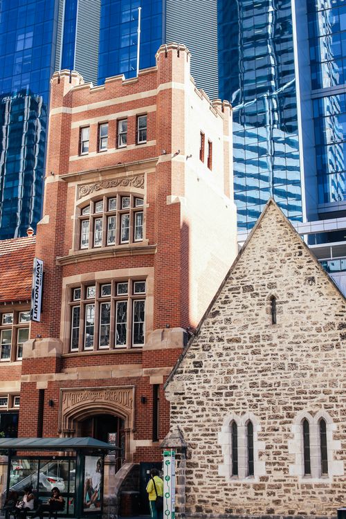 Free A striking juxtaposition of historic redbrick and stone buildings against modern skyscrapers under a clear blue sky. Stock Photo
