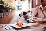 Person Pouring Wine on Brown Wooden Table