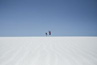 Person in Black Jacket and Pants Jumping on Brown Sand