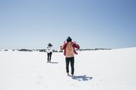 Man and Woman Walking on Snow Covered Ground