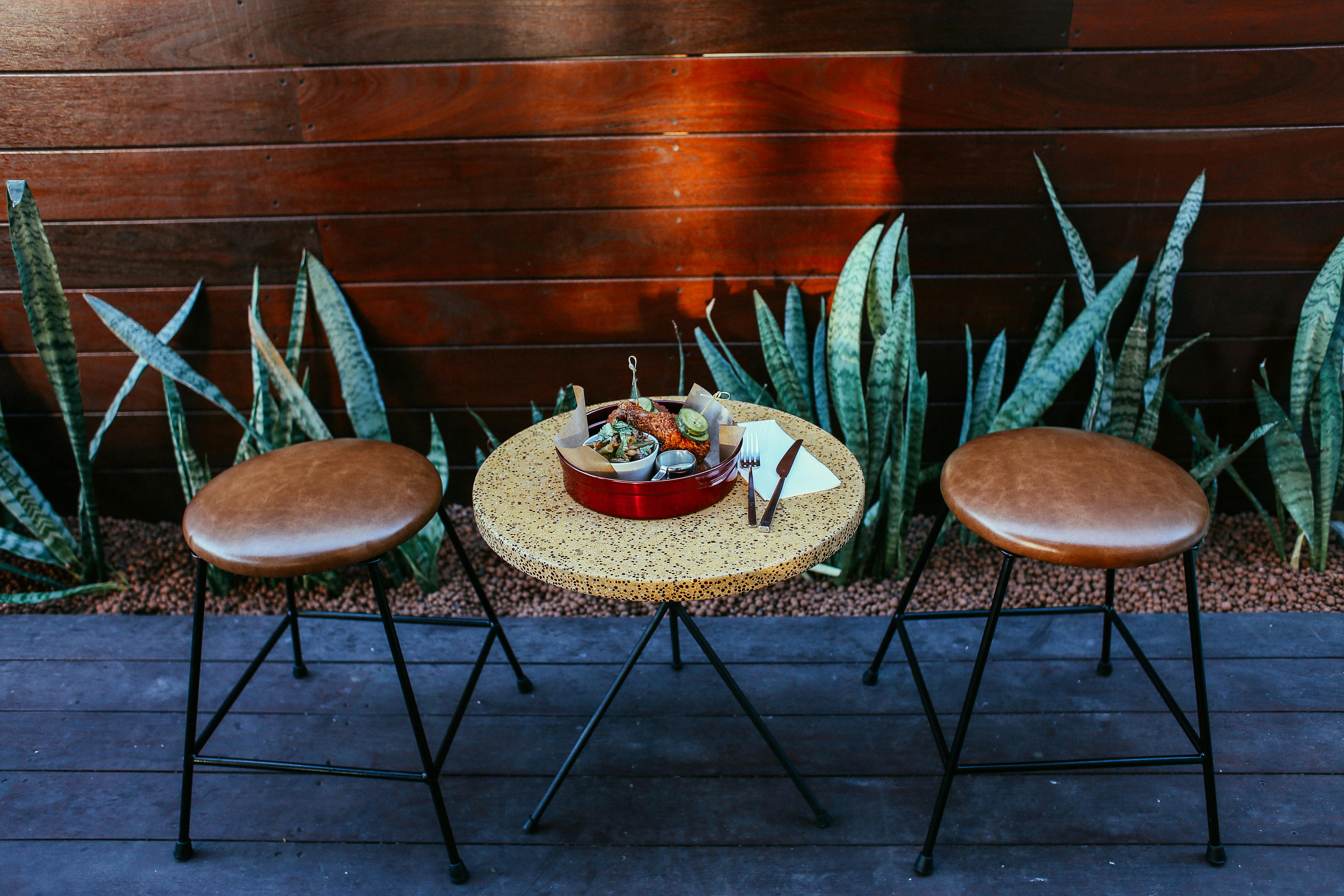 Free Inviting outdoor setting with round table, chairs, and a meal amidst plants. Stock Photo