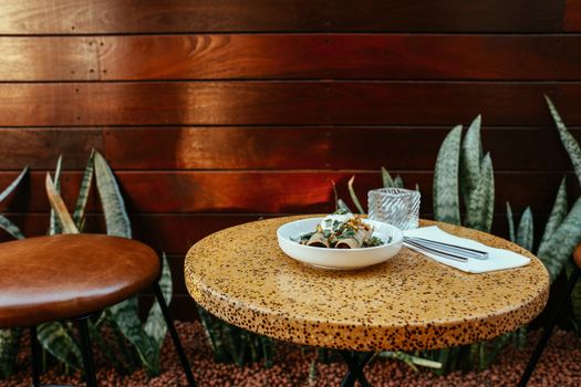 Cozy outdoor restaurant table with a beautifully presented gourmet bowl dish.