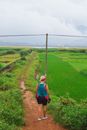 Woman Walking on Dirt Road Through Fiel