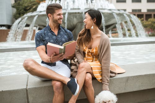 Free Couple Reading Book by a Fountain  Stock Photo