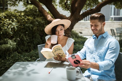 Free A Couple Sitting on a Chair while Reading Books Together Stock Photo