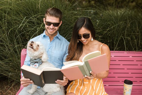 Beyaz Uzun Kaplamalı Küçük Köpek Ile Kırmızı Bankta Oturan Güneş Gözlüğü Takan Mavi Gömlekli Kadın