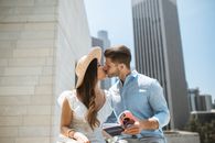 一对异族夫妇在摩天大楼的户外深情接吻，唤起了浪漫的共鸣