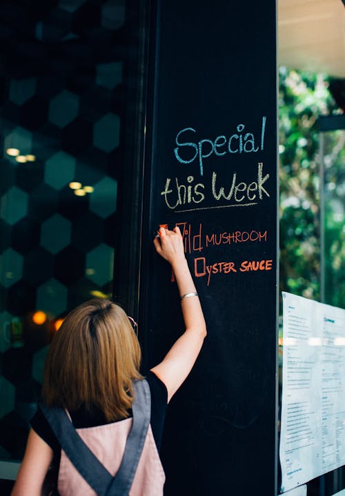 Free Woman Writing with Chalk on Board in Restaurant  Stock Photo