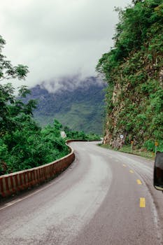 蜿蜒的高速公路穿过郁郁葱葱的绿色山脉，在多云的天空下，吸引着人们去旅行和探索