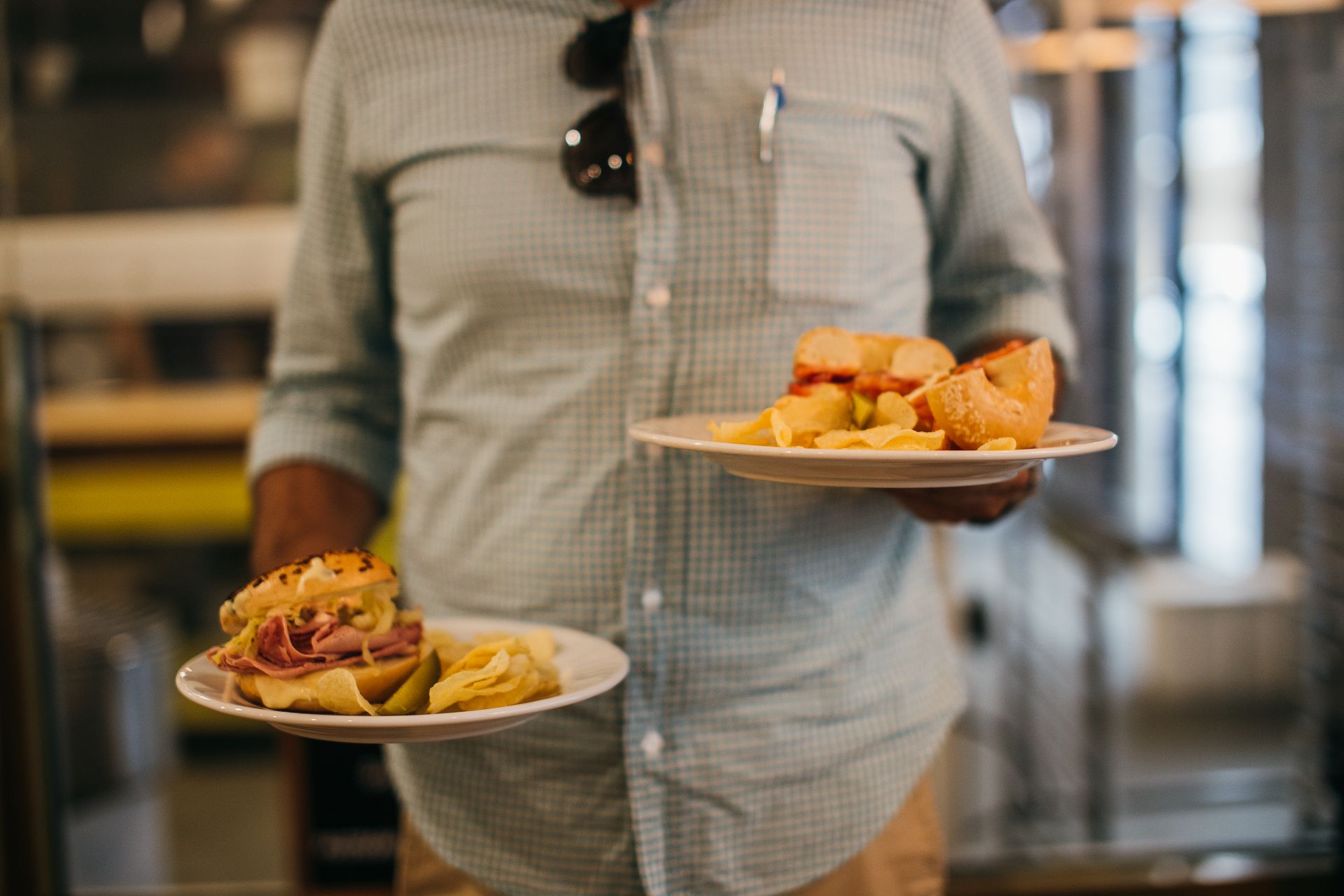 Man in Plaid Shirt Holding Two Plates with Crisps and Sandwiches