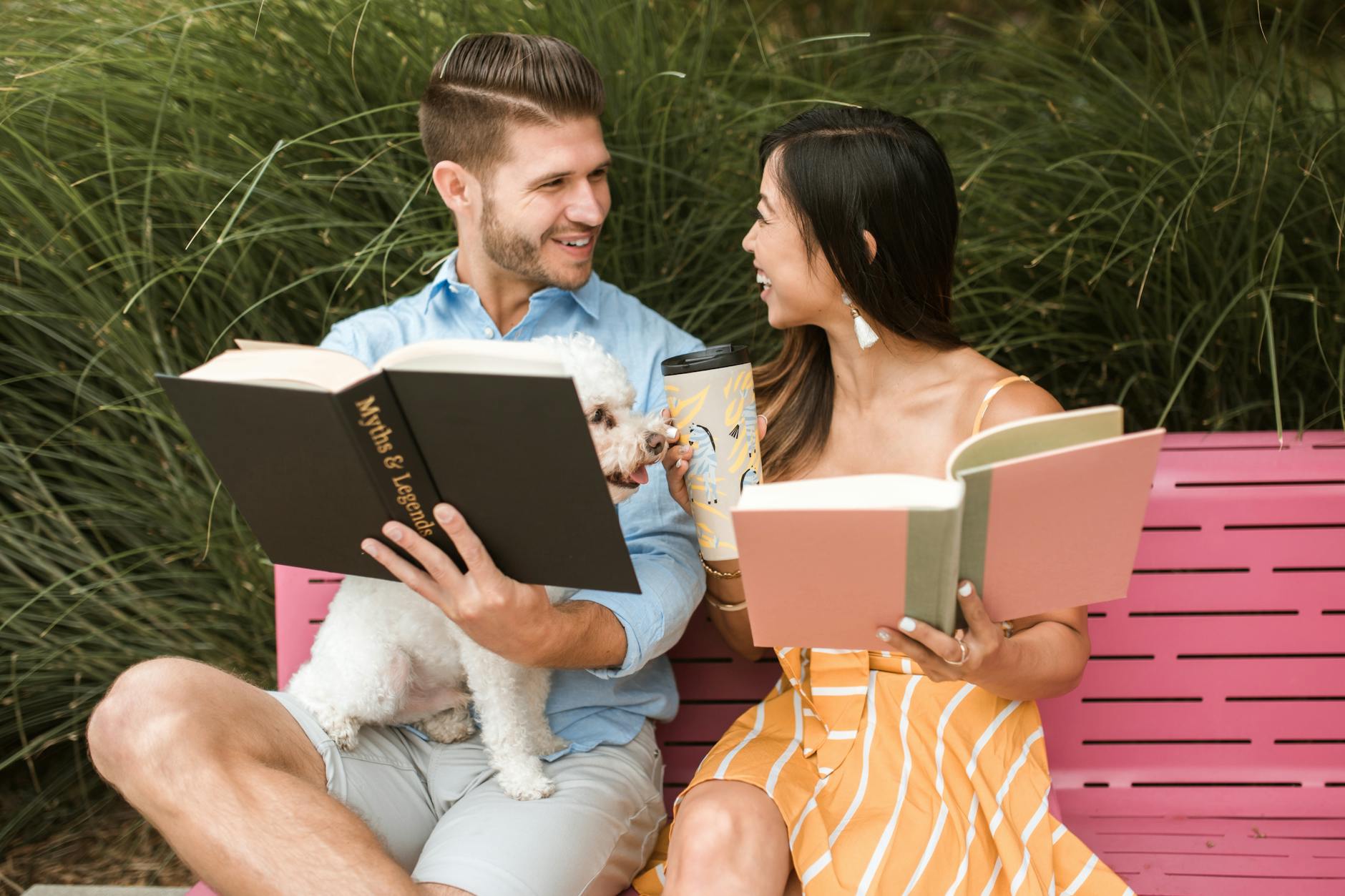 Happy interracial couple enjoying a relaxing day outdoors reading with their pet dog.