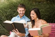 Man in Blue Dress Shirt Holding Black Book Beside Woman in White Sleeveless Dress