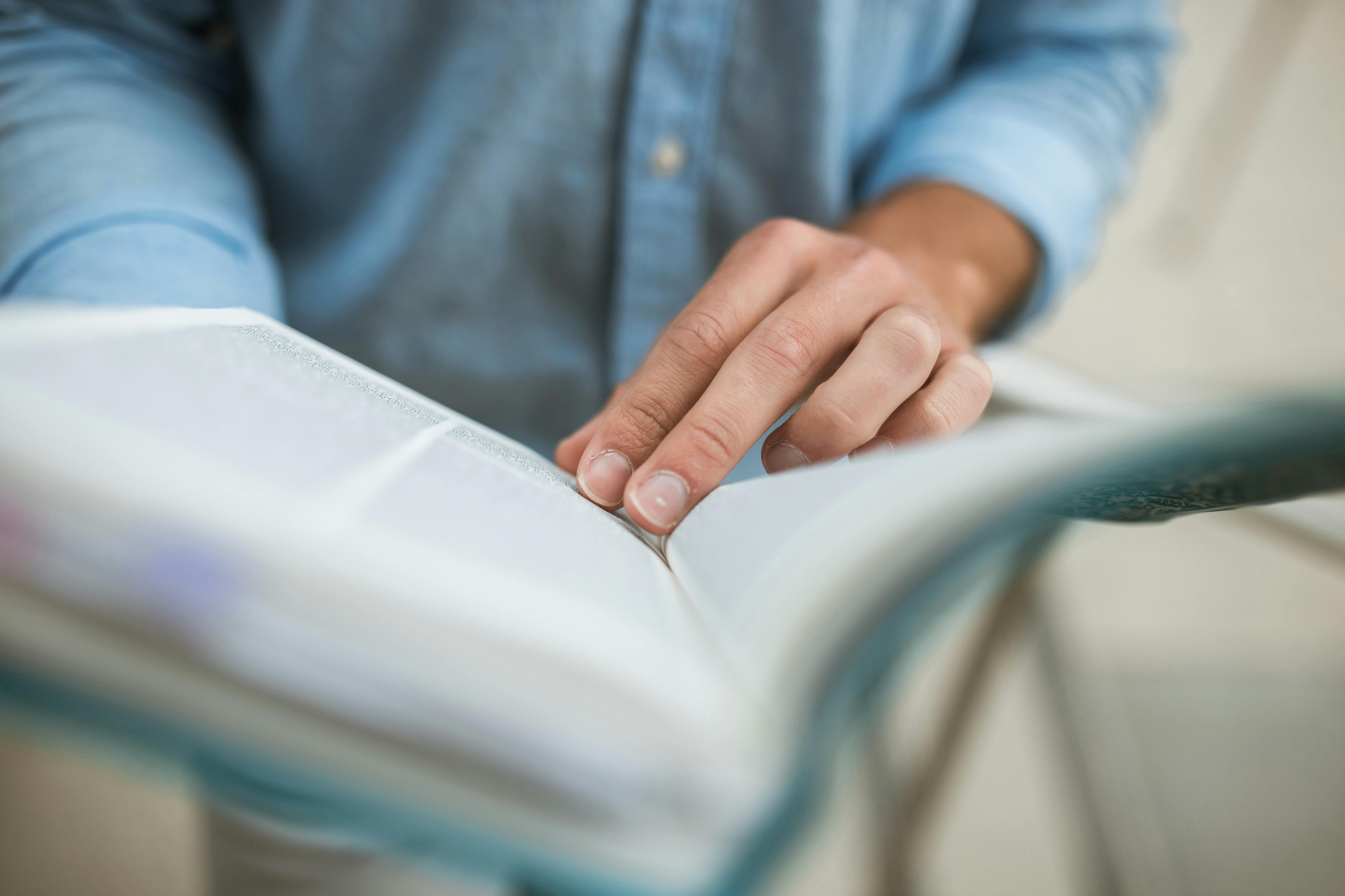 person in blue long sleeve shirt flipping the book page